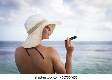 woman in white hat and with cigar standing in water on caribbean beach - Powered by Shutterstock