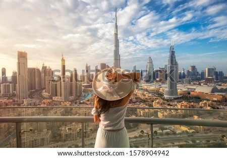 Woman with a white hat is standing on a balcony in front of the skyline from Dubai
Downtown