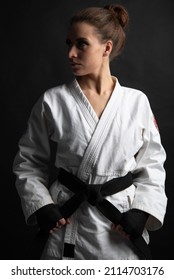 A Woman In A White Kimono And Black Sash Looks Away With Her Hands Down.