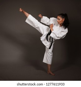 Frauen in weißem Kimono treten hoch in die Luft - ein Karate-Kampfmädchen