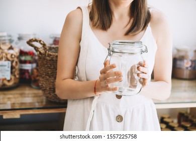 Woman in white linen dress with empty glass jar buying in sustainable plastic free grocery store. Girl with reusable cotton bag and wicker basket in zero waste shop. Minimalist low waste lifestyle - Powered by Shutterstock