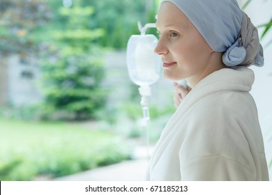 Woman in white robe smiling and looking out the window