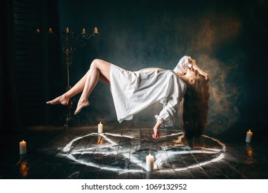 Woman in white shirt flying over pentagram circle - Shutterstock ID 1069132952