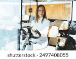 A woman in a white shirt sits behind the wheel of a golf cart, focused and thoughtful. The vehicle