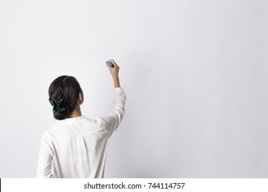 Woman In White Shirt Writing On Imaginary Screen/whiteboard With Blue Marker On White Background. Back View. Half Length Portrait. Teacher/office Worker.