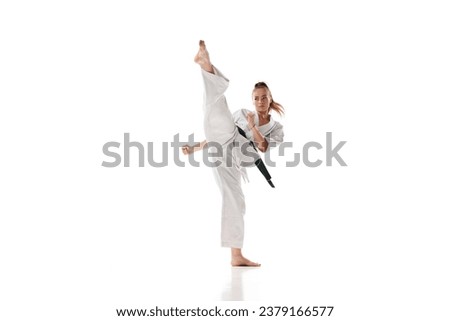 Woman in white sport karate uniform with black belt training in action against white studio background. Concept of professional sport, recreation, art, hobby, culture. Copy space for ad.