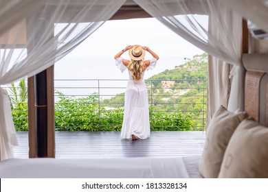 Woman In White Summer Dress In Hotel Room On Vacation With Amazing Tropical View From Balcony