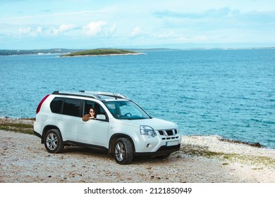 woman in white suv car at sea beach. bay on background. car travel concept