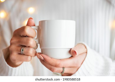 Woman in a white sweater with a white cup mockup