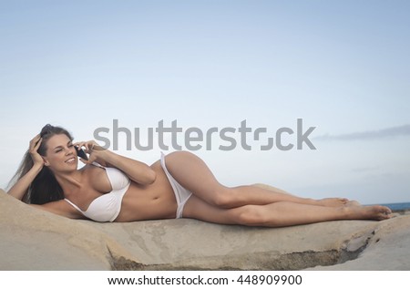 Woman in white swimsuit doing a phone call