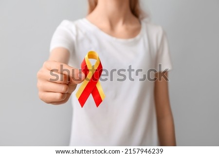 Woman in white t-shirt with awareness ribbon on grey background, closeup. Hepatitis concept