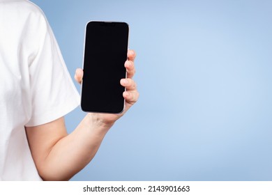 Woman With White T-shirt Holding Cell Phone In Her Hand And Showing Smartphone Screen Direct To Camera. Front View