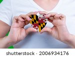 Woman in white t-shirt holds a heart in the form flag Maryland on her chest. Photo for a postcard on Flag Day, Independence Day, travel, patriotism, other holiday