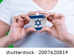Woman in white t-shirt holds a heart in the form flag Israel on her chest. Photo for a postcard on Flag Day, Independence Day, travel, patriotism, other holiday