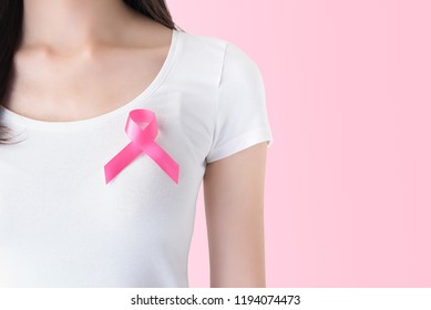 Woman in white t-shirt with satin pink ribbon on her chest, supporting symbol of breast cancer awareness campaign in October - Shutterstock ID 1194074473