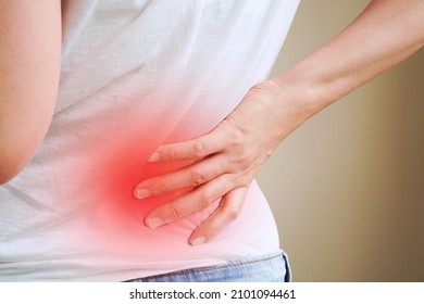 Woman In White T-shirt Touch Her Waist And Hold Lower Back With Red Spot Area Which Suffering From Back Pain Or Back Ache