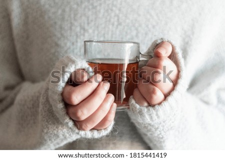 Woman with white wool sweater holding a cup of hot