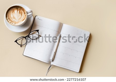 A woman who is keeping a diary note on a gray business table, background top view with glasses, coffee cups and copy space