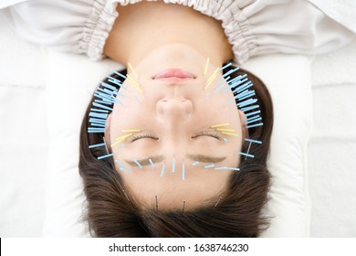 Up of a woman who is struck with acupuncture in the face in acupuncture clinic