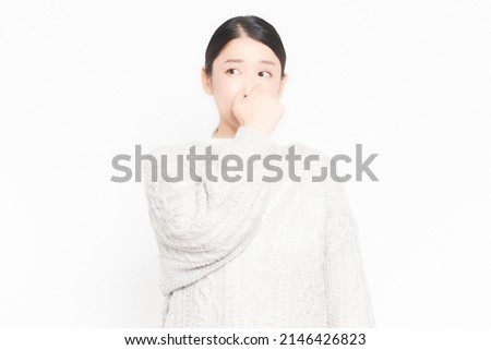 A woman who is suffering from stinks and is pinching her nose