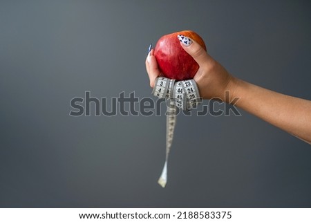 woman who wants to lose weight with a apple and a tape measure isolated on a gray background. health concept