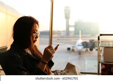 woman who wearing glasses is looking at smart phone at airport with playful face - Shutterstock ID 652961701