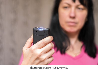 A Woman Will Use A Stun Gun With A Powerful Electric Discharge. The Girl Holds A Personal Taser In Her Hands To Protect Against Bandits. The Female Turned On The Device For Her Protection.