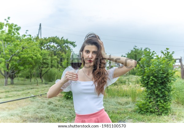 woman with wine, woman with glass of wine, woman\
drinking red wine in the\
garden