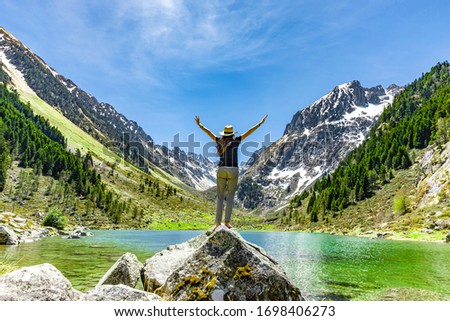 Woman in winner pose on a rock at a mountain lake
