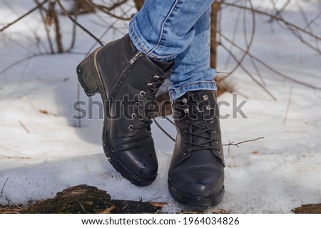 Woman winter boots on snow. Black winter shoes. A pair of warm winter boots on your feet.