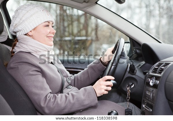 Woman in\
winter clothes driving a car looking\
forward