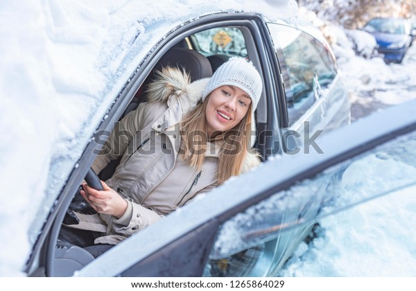 Woman at\
winter time. Yoyng female looking in window of her car at snowly\
winter day. Winter car. Woman at winter time.\
