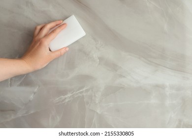 a woman wipes a gray tile with a melanin sponge. close-up