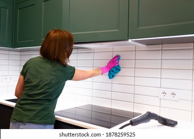 Woman wipes tiles in the kitchen. Cleaning employee cleans the house