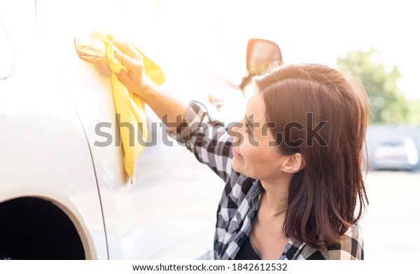 Woman\
wiping car door handle with rag during car\
wash