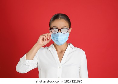 Woman Wiping Foggy Glasses Caused By Wearing Medical Mask On Red Background