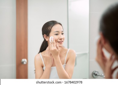 Woman Wiping Her Face With Cotton Pad In The Bathroom