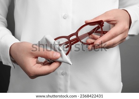 Woman wiping her glasses with microfiber cloth on grey background, closeup Foto d'archivio © 