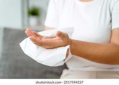 A woman is wiping her hands with a paper towel. Concept of cleanliness and hygiene, as the woman is taking care of her hands - Powered by Shutterstock