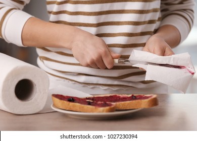 Woman Wiping Knife With Paper Towel In Kitchen