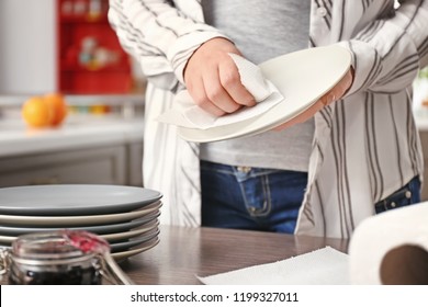 Woman Wiping Plate With Paper Towel In Kitchen