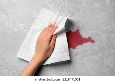 Woman Wiping Spilled Juice With Paper Napkin On Grey Surface, Top View