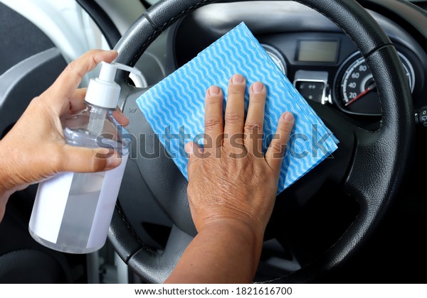 Woman wiping steering wheel with alcohol and blue\
cloth cleaning car. Interior Cleaning. Covid-19 prevention.\
Disinfecting car.