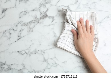 Woman Wiping White Marble Table With Kitchen Towel, Top View. Space For Text