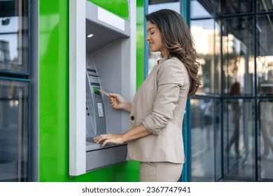 Woman withdrawing cash at an ATM. Young woman withdrawing money from credit card at ATM