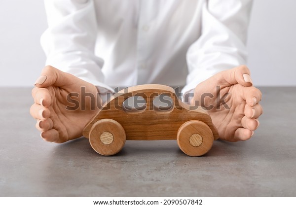 Woman with wooden car in office, closeup.\
Concept of automobile\
insurance
