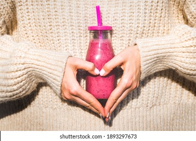 Woman In Woollen Sweater Making Heart Shape With Her Hands And Holding Bottle With Pink Homemade Detox Blueberry And Raspberry Smoothie Or Juice. Healthy Clean Eating