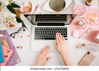 Woman work on laptop. Creative desk workspace with computer, clips, flowers, cosmetics, glasses. Flat lay style. Freelance and remote work concept