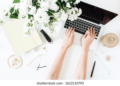 Woman Work On Laptop. Office Desk Workspace With Computer, Flowers Bouquet And Stationery On White Table. Flat Lay, Top View Work / Business Hero Header Background.