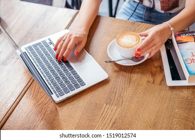 Woman at work or study in a cafe. She drinks coffee and do business using her laptop. Copy space